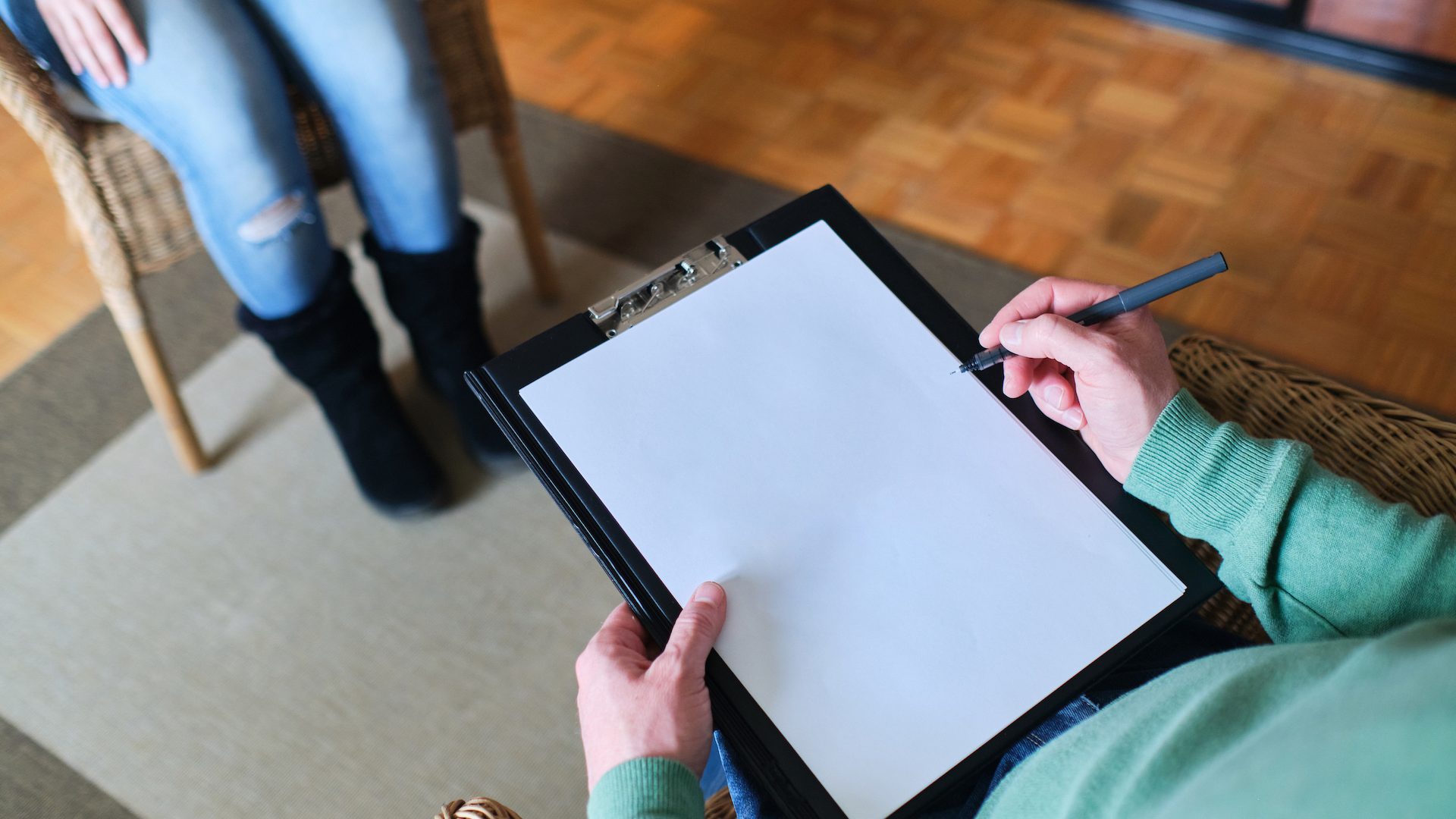 Close-up of therapist hand writing notes during a counseling session with a single woman sitting on a couch in the blurred background.enneagram of personality - nine distinct types